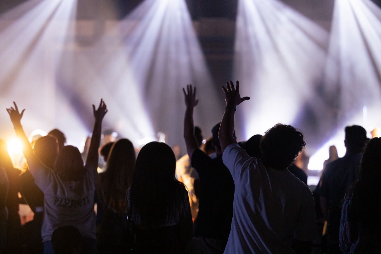 An evening worship gathering with the congregation lit from the stage